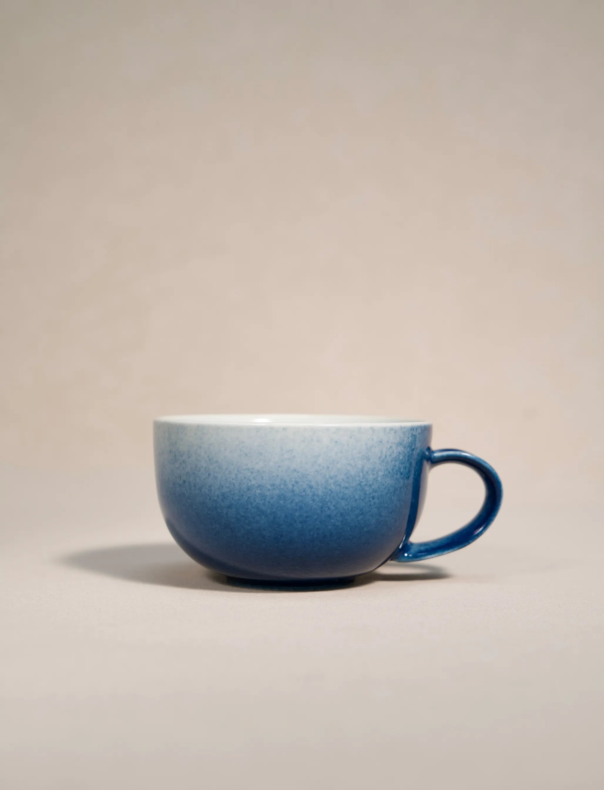 SaraGaia artisan porcelain cup featuring a gradient sprinkling blue snowflake glaze effect.