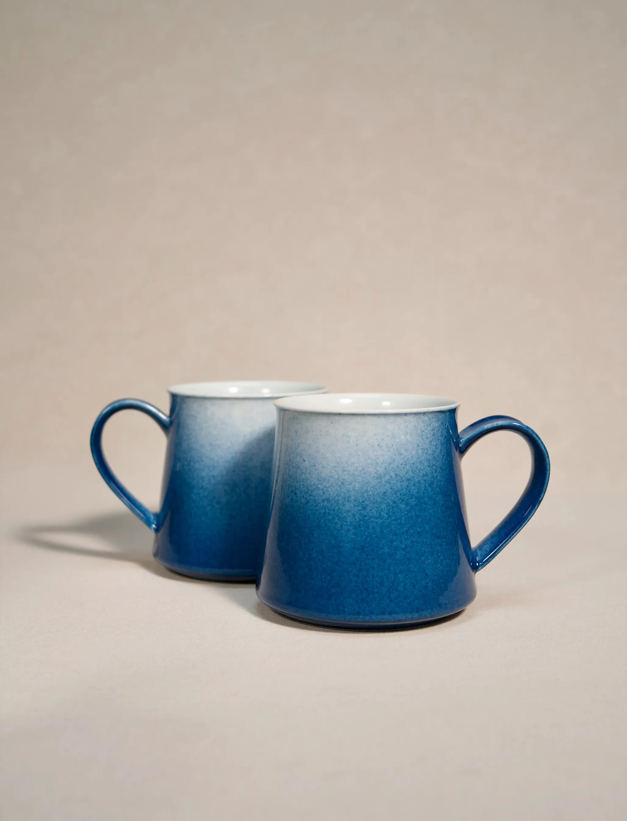 A set of two SaraGaia artisan porcelain mugs, featuring a gradient sprinkling blue glaze effect.