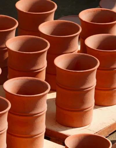 Row of stacked terracotta clay bamboo-form cups, air-drying before high-fire kilning. Showcasing the authentic bisque stage of the detailed 72-step handcrafted Jingdezhen porcelain process.