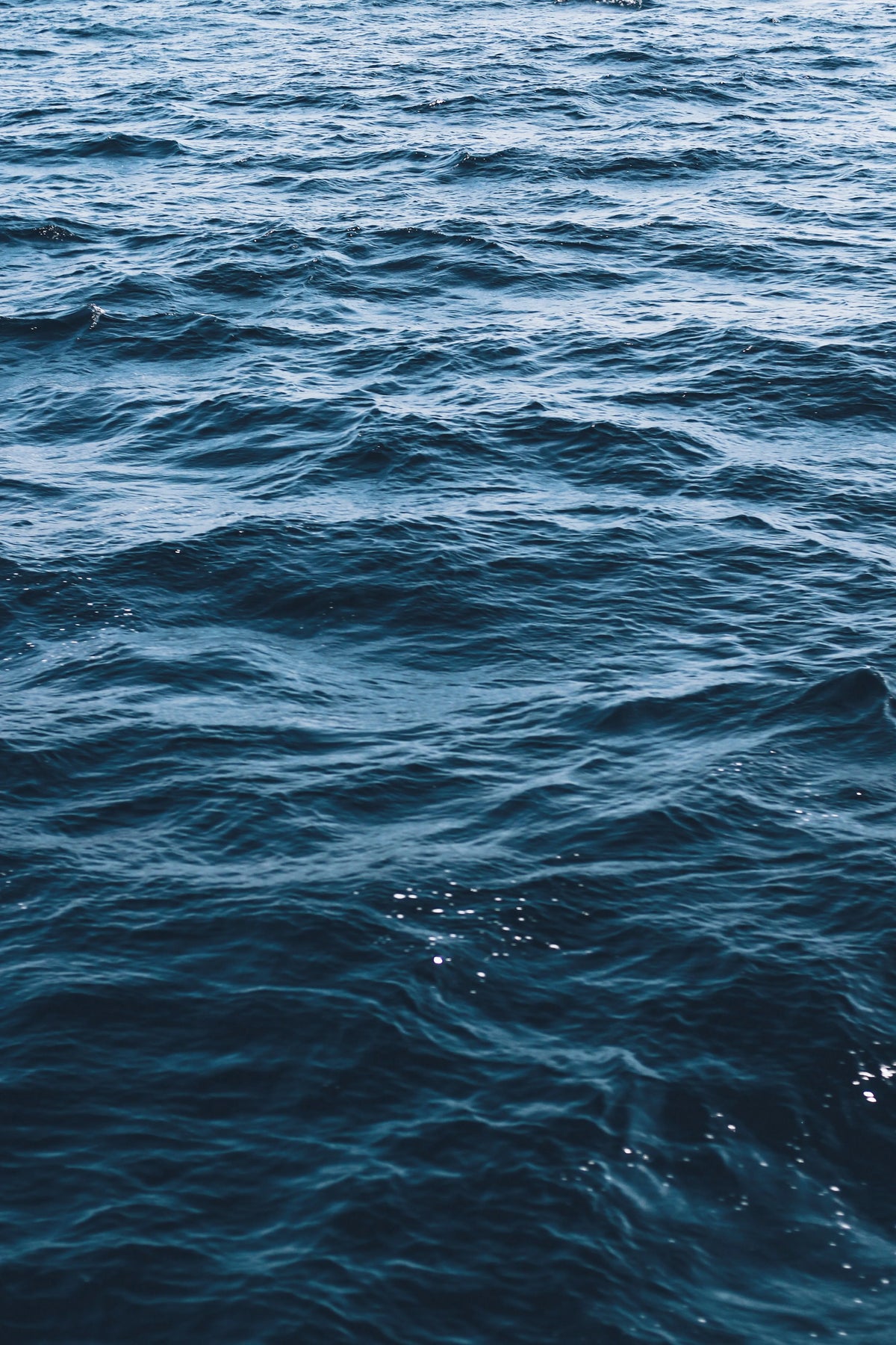 Rippling deep blue ocean water with gentle wave textures, capturing the natural aquatic inspiration for Saragaia's ceramic glaze collection.