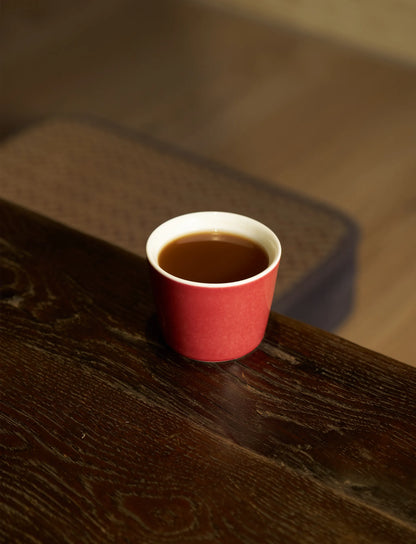 6.8oz SaraGaia red cup on a dark wood table. Elegant traditional tea ritual.