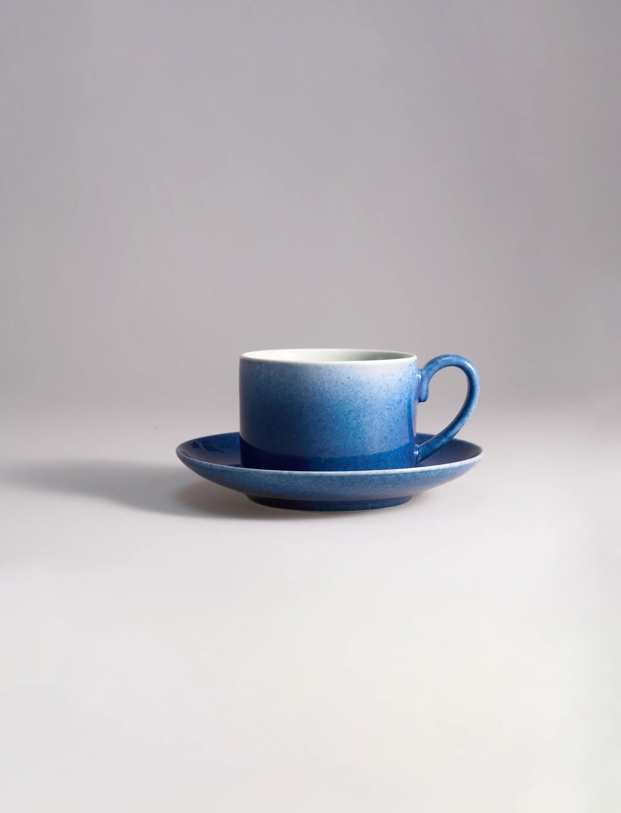 SaraGaia artisan porcelain coffee cup with saucer, featuring gradient sprinkling blue textures.