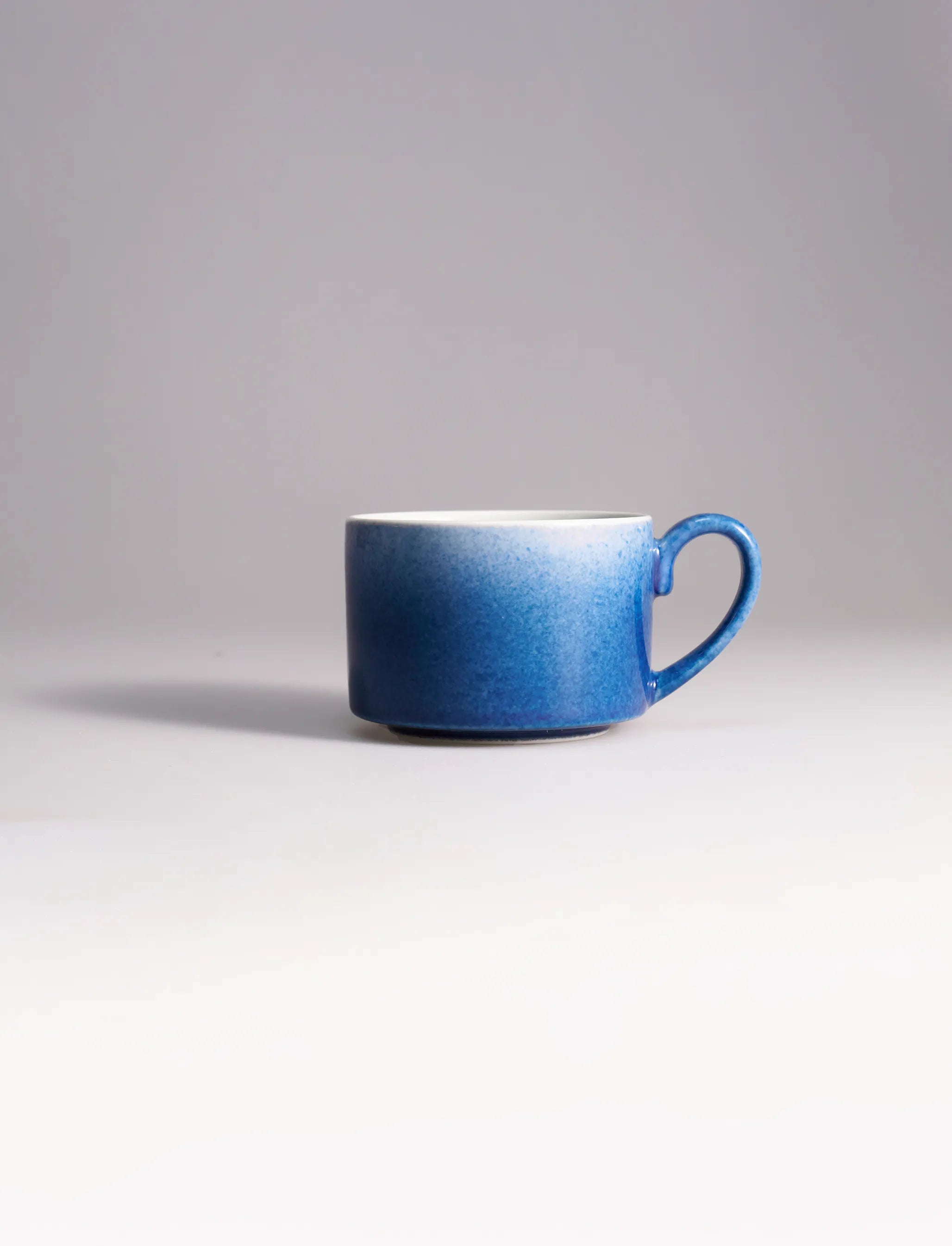 SaraGaia artisan porcelain cup featuring a stunning gradient sprinkling blue snowflake glaze effect.