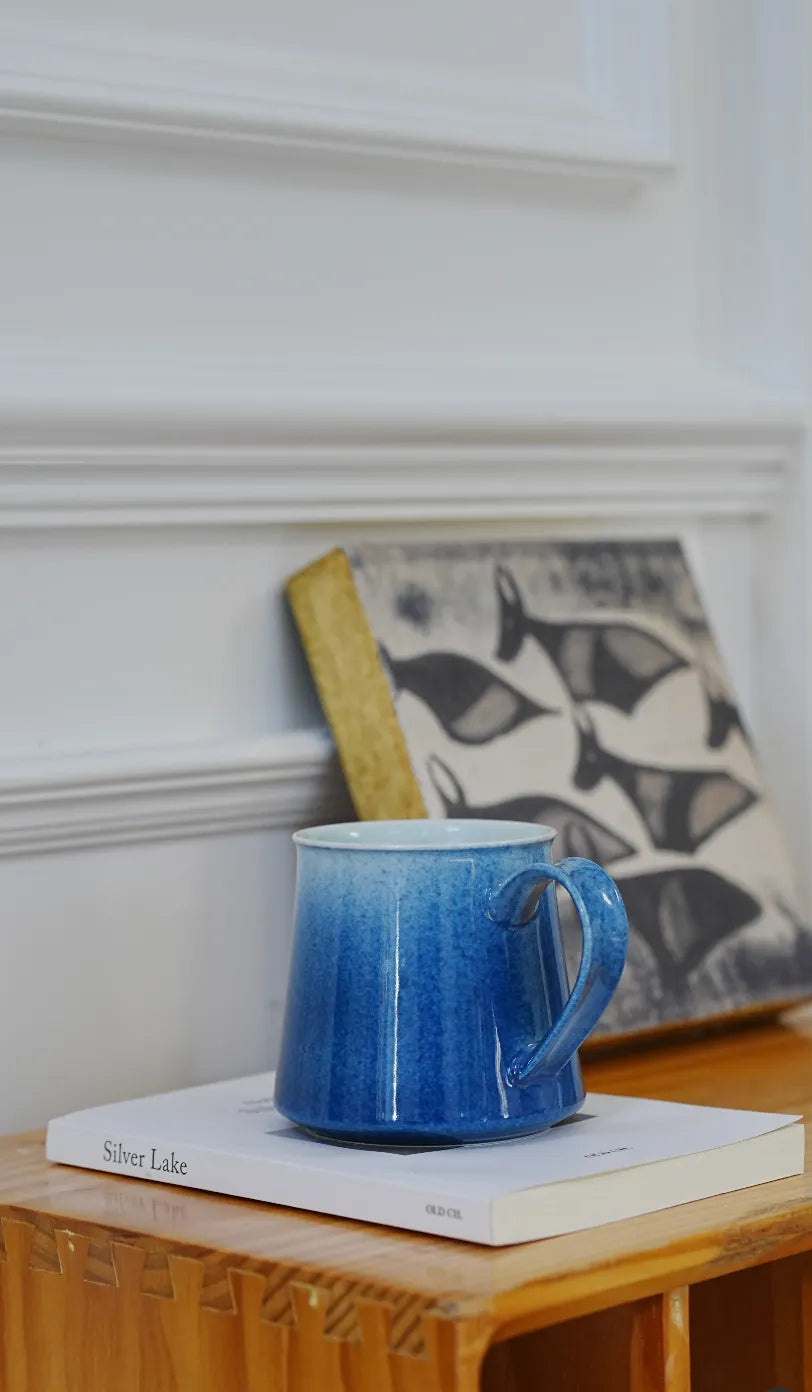SaraGaia artisan porcelain mug on a book, showcasing elegant minimalist home library aesthetics.