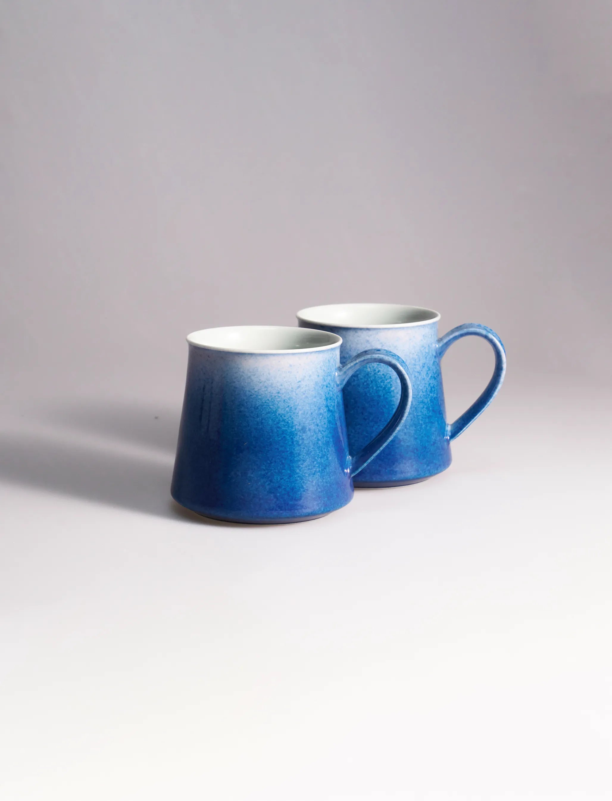 A set of two SaraGaia artisan porcelain mugs, featuring a gradient sprinkling blue glaze effect.