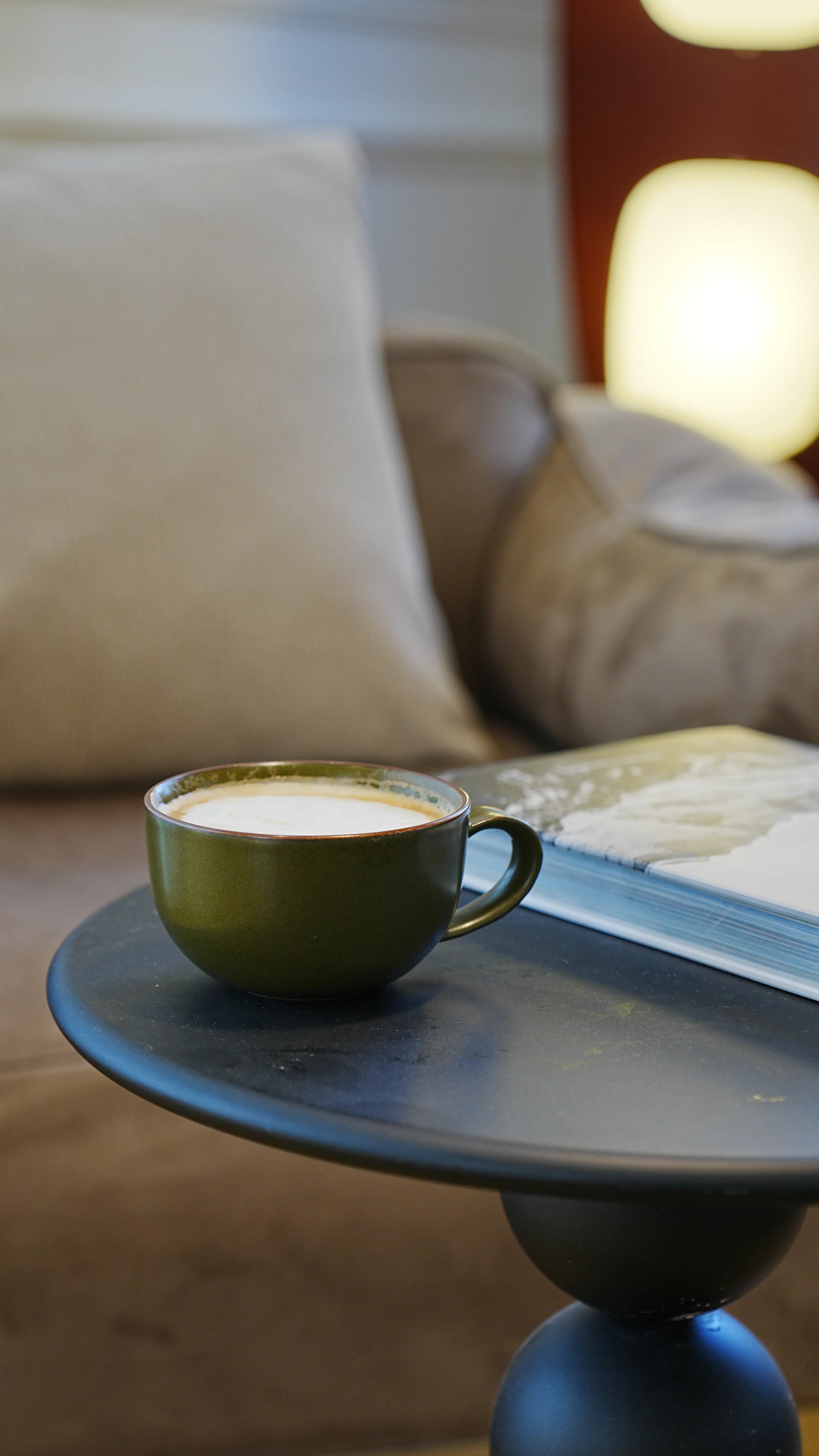SaraGaia bamboo-shaped olive green porcelain cup on a wood stand in natural window sunlight.