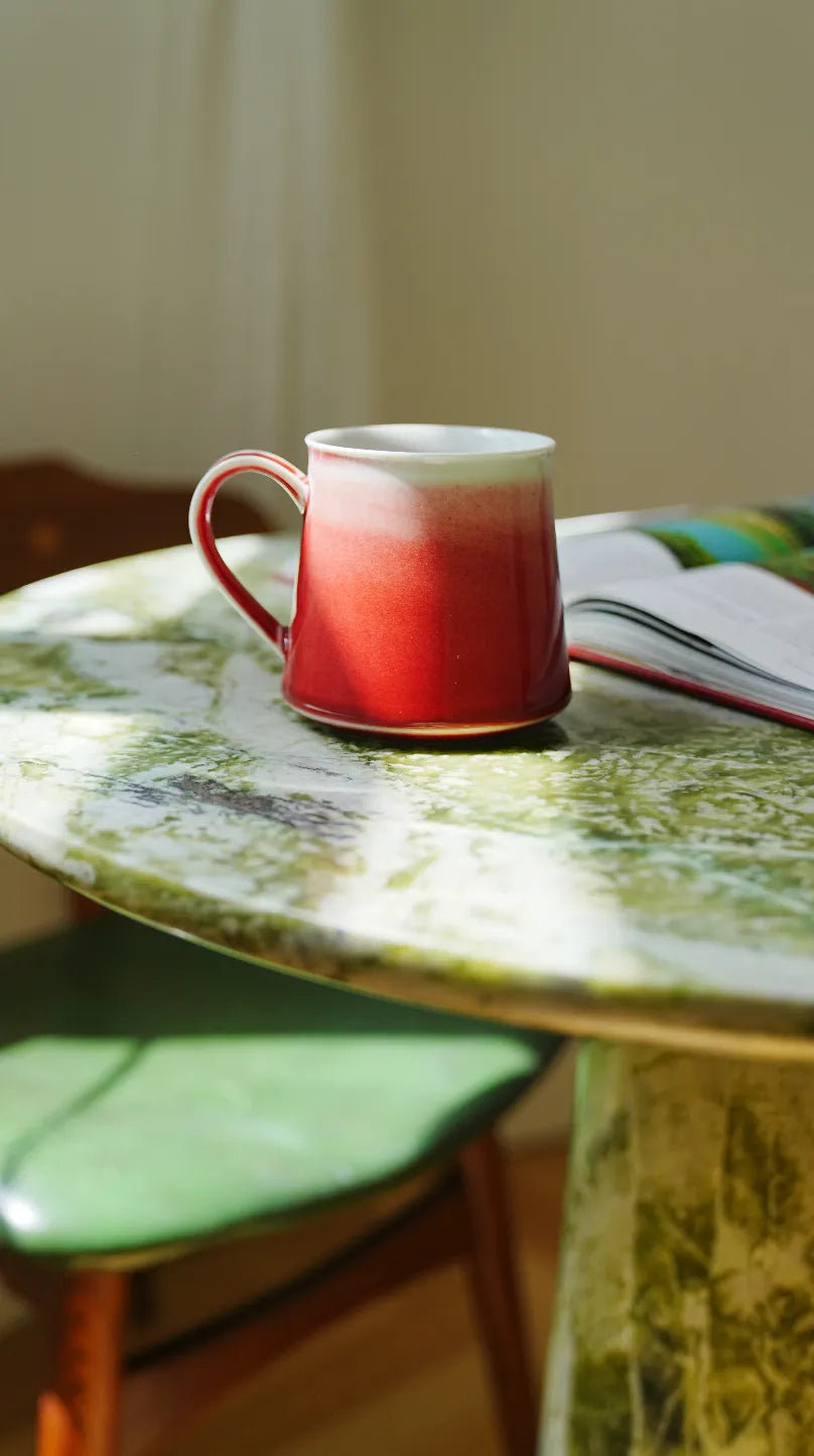 SaraGaia handcrafted peach bloom porcelain mug on a table, showcasing luxury artisan craftsmanship.