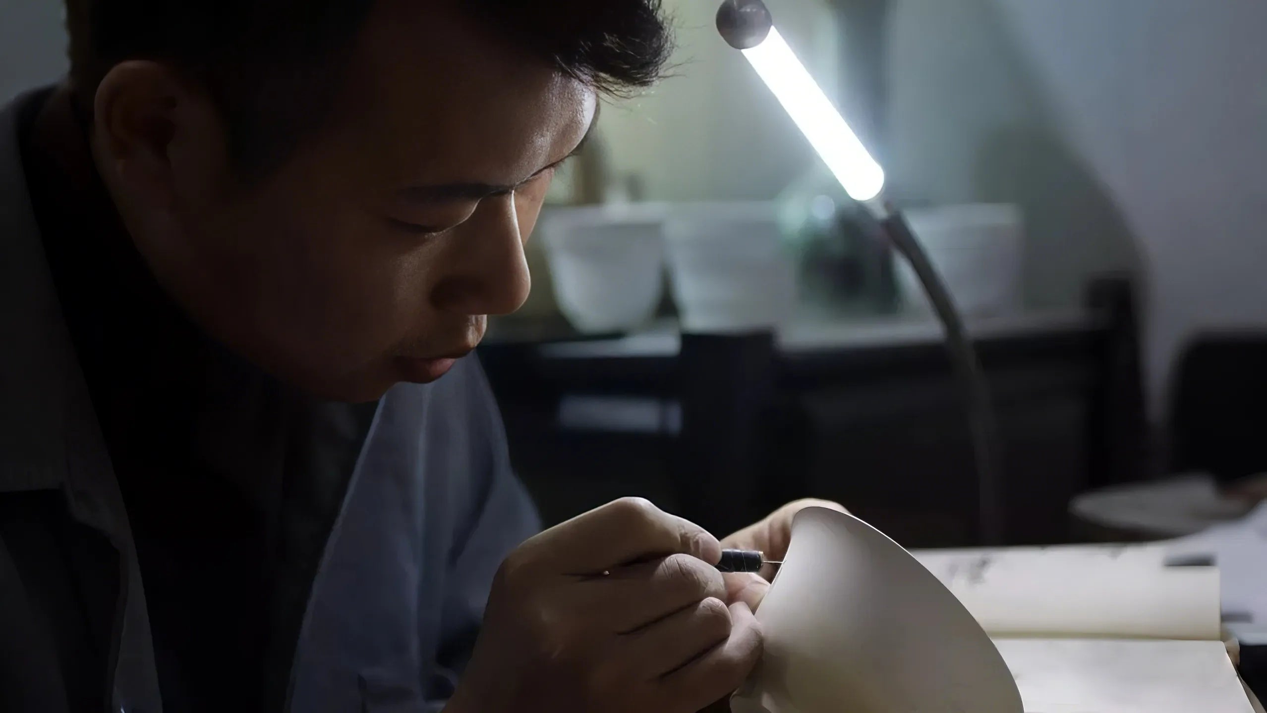 Saragaia craftsman hand-carving a Jingdezhen porcelain cup profile in a studio.
