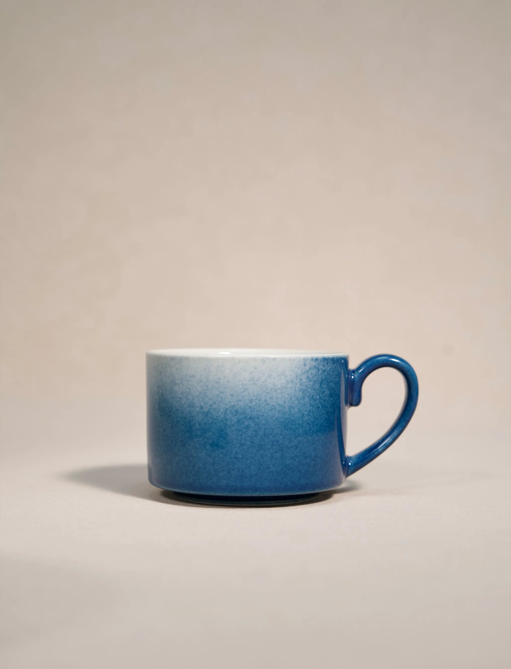 SaraGaia artisan porcelain cup featuring a stunning gradient sprinkling blue snowflake glaze effect.