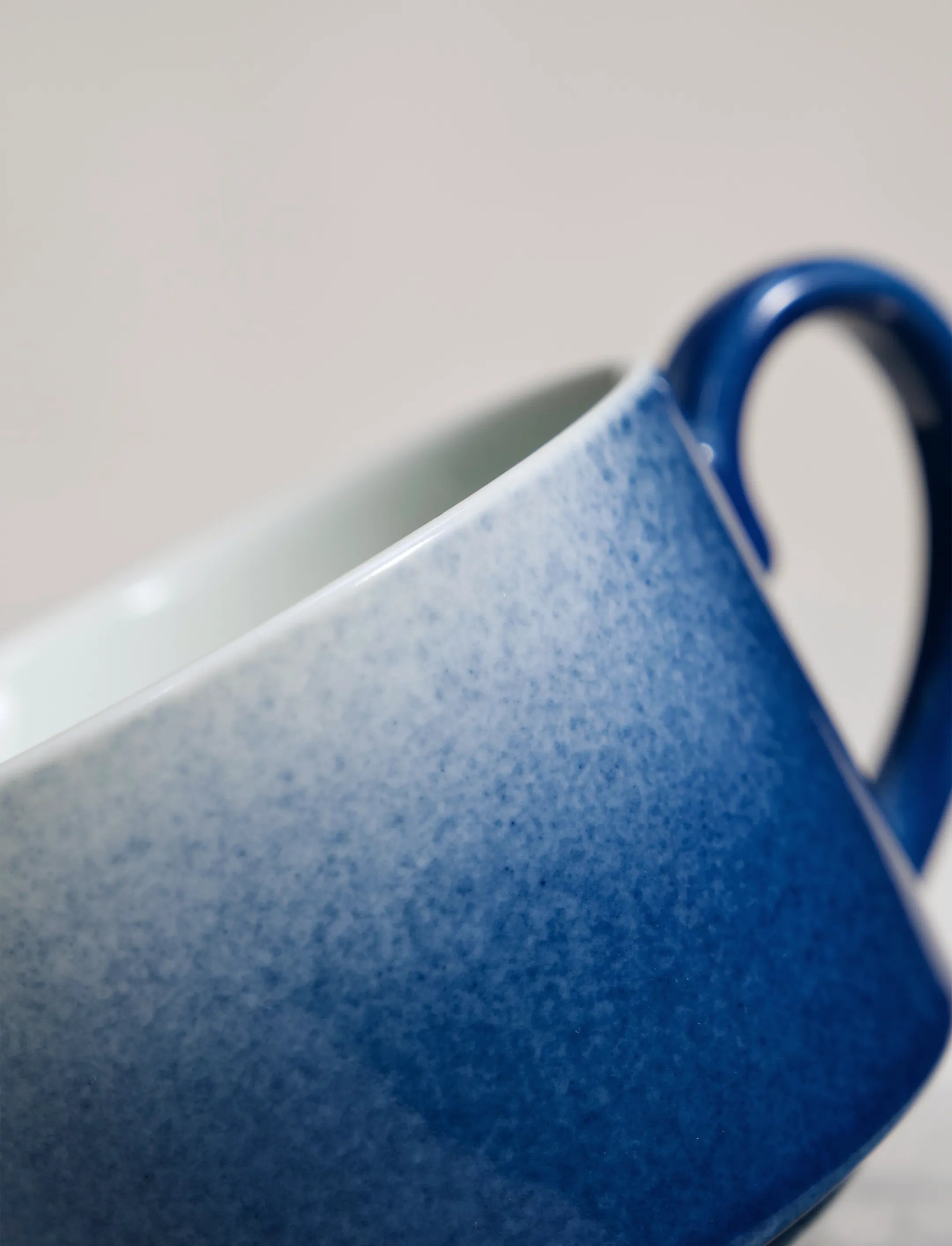 Close-up of SaraGaia artisan porcelain cup, revealing the gradient sprinkling blue glaze texture.