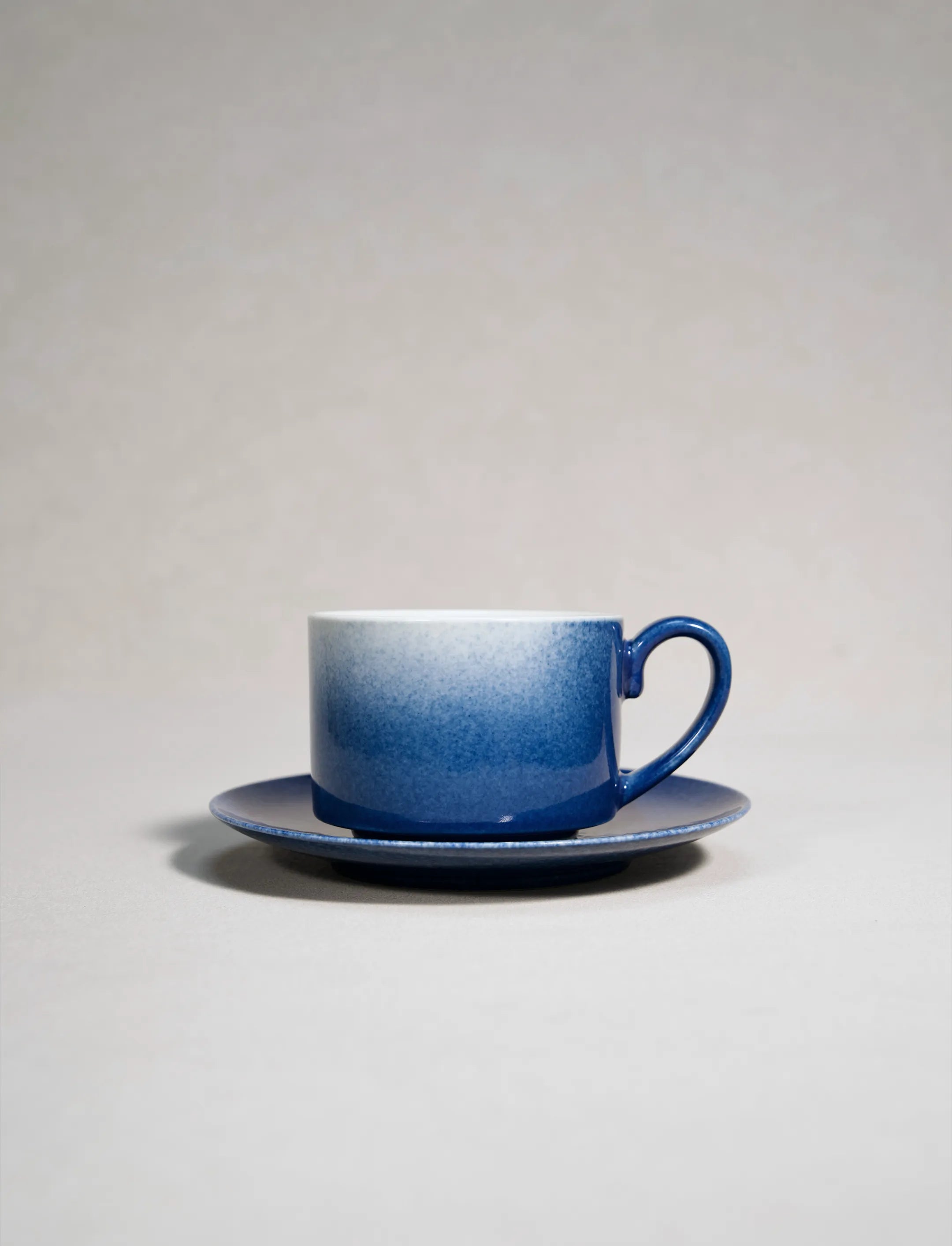 SaraGaia artisan porcelain coffee cup with saucer, featuring gradient sprinkling blue textures.