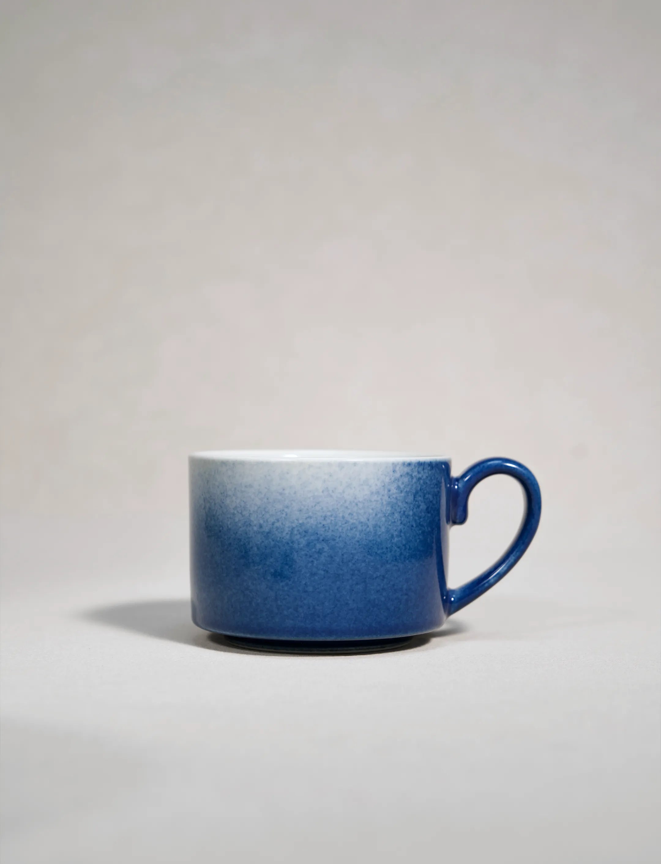 SaraGaia artisan porcelain cup featuring a stunning gradient sprinkling blue snowflake glaze effect.