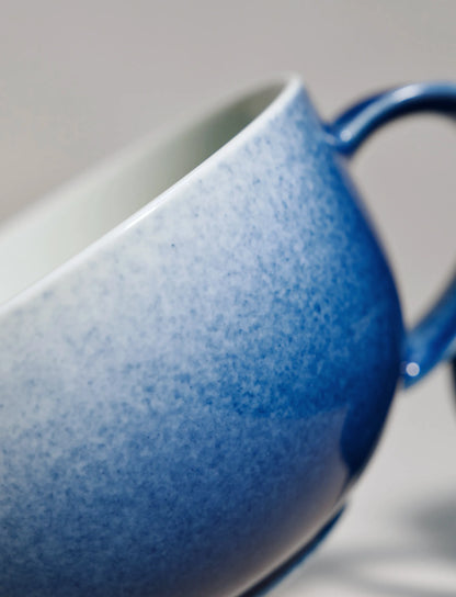Close-up of SaraGaia luxury porcelain cup, highlighting the gradient sprinkling blue glaze texture.