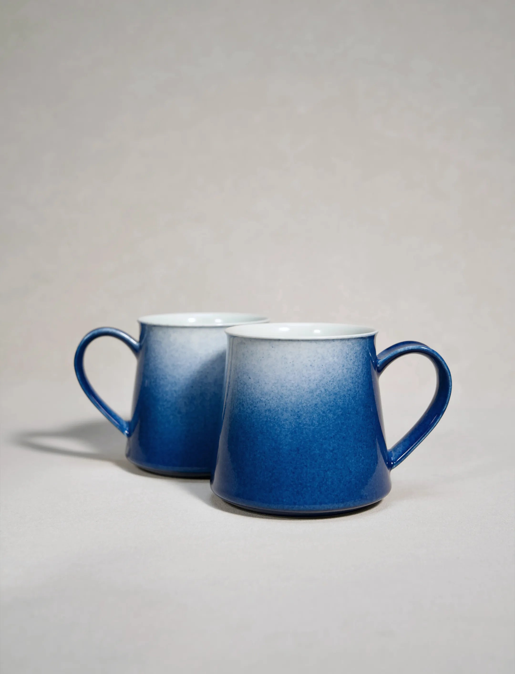 A set of two SaraGaia artisan porcelain mugs, featuring a gradient sprinkling blue glaze effect.