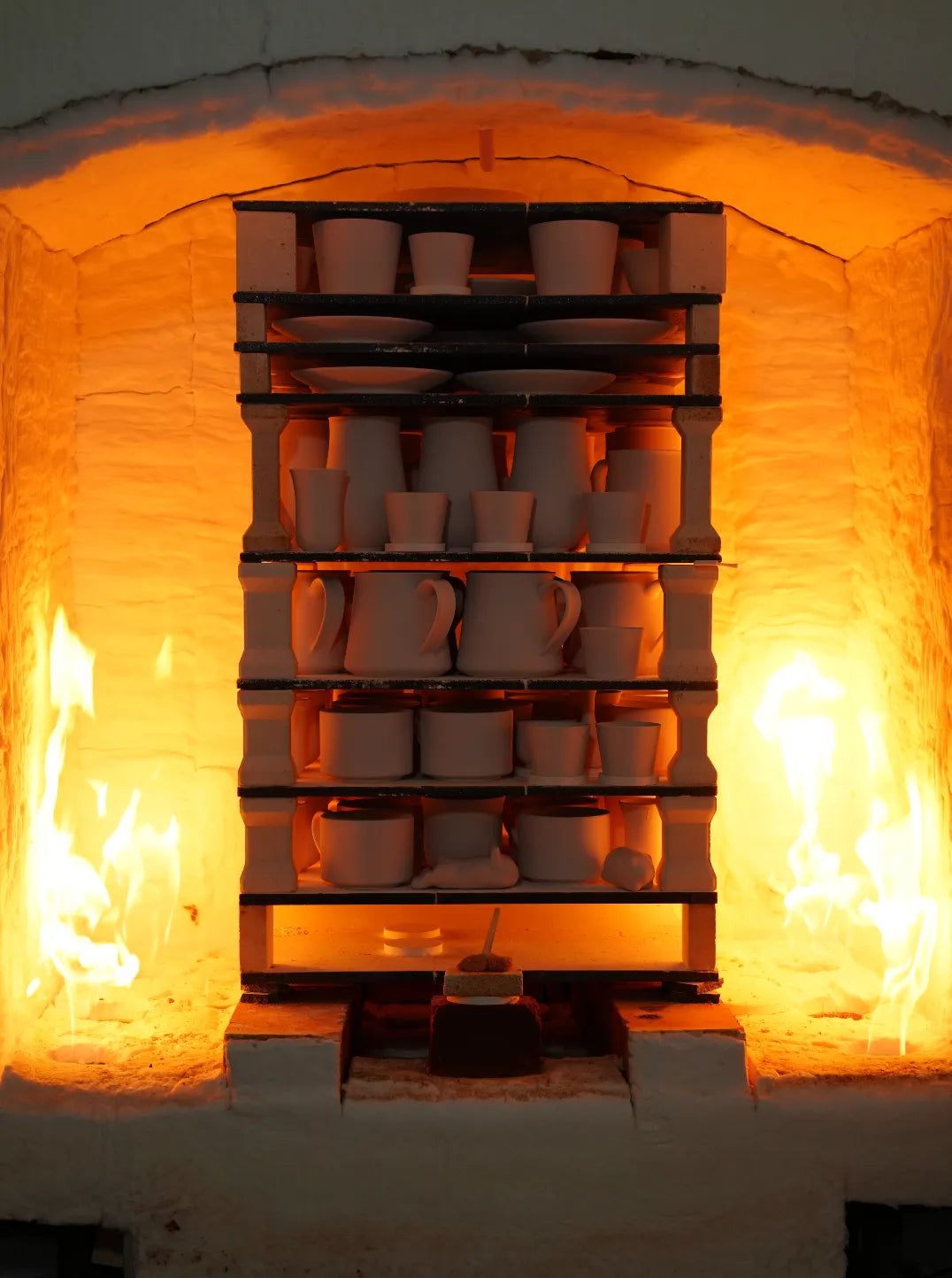SaraGaia handmade Jingdezhen porcelain firing in a high-temperature kiln with roaring flames, showcasing heritage craftsmanship.