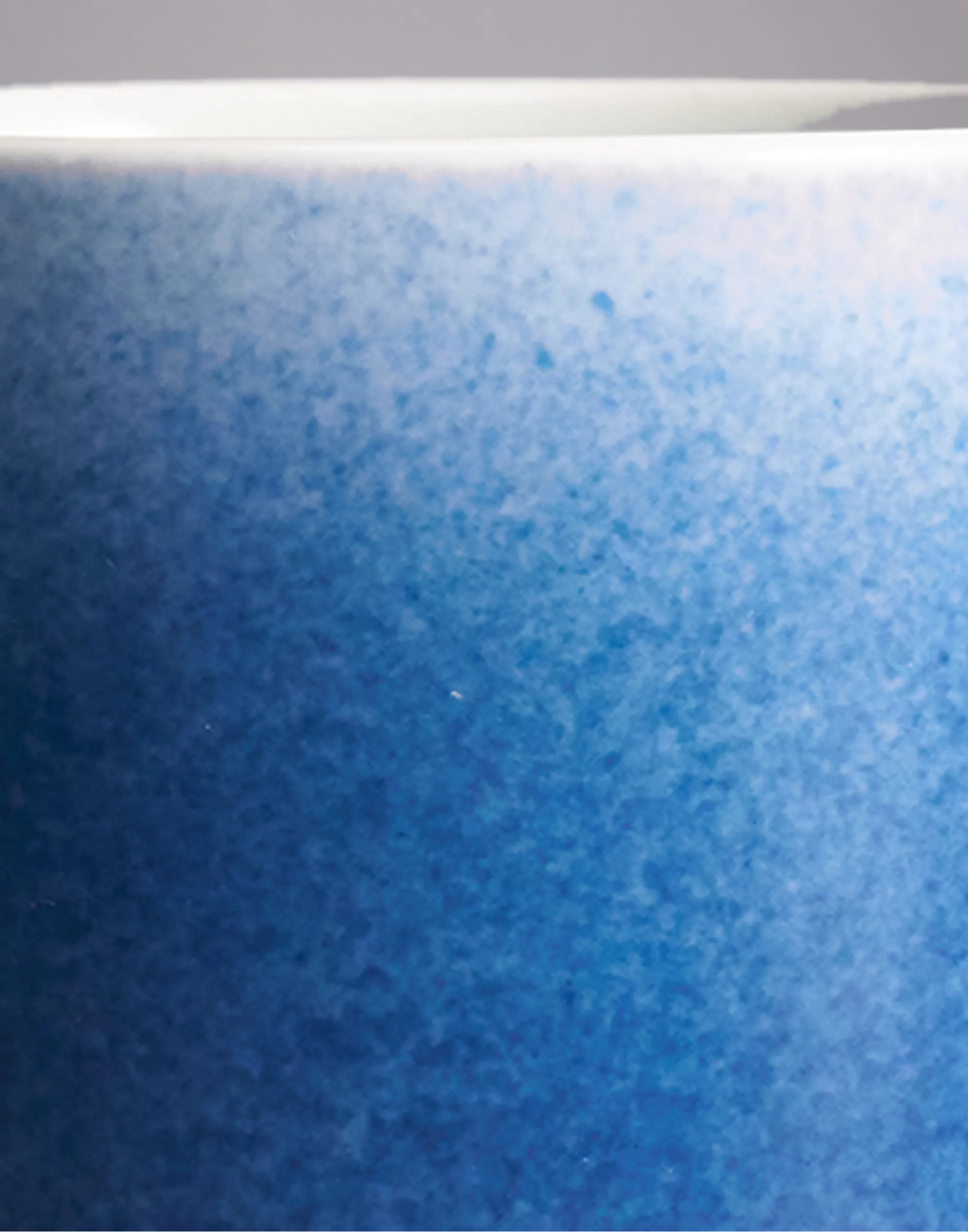 Close-up of SaraGaia luxury porcelain cup, highlighting the gradient sprinkling blue glaze texture.