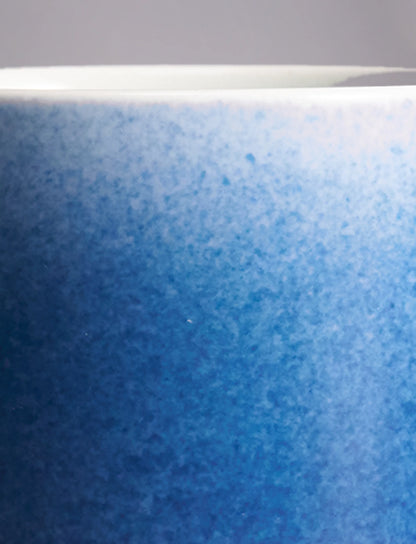 Close-up of SaraGaia luxury porcelain cup, highlighting the gradient sprinkling blue glaze texture.