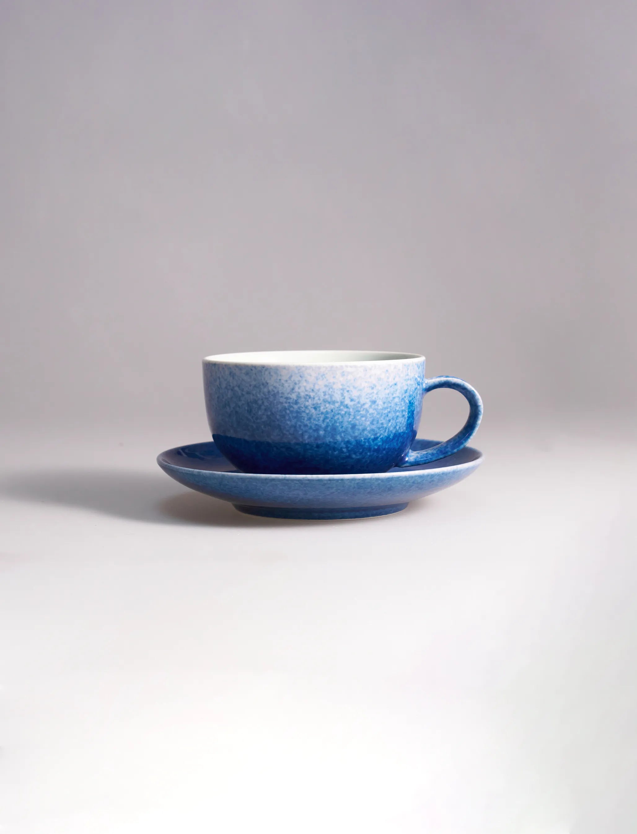 SaraGaia luxury porcelain latte cup with saucer, featuring a sprinkling blue snowflake glaze.