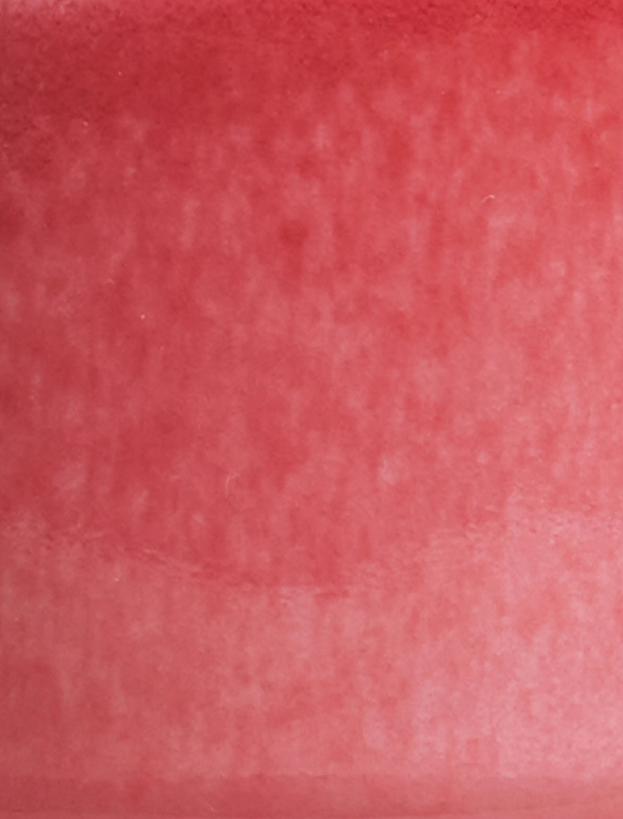 Close-up of SaraGaia porcelain cup showcasing mottled crimson tones of copper peach bloom glaze.