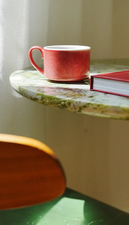 SaraGaia peach bloom porcelain cup on a green marble table, showcasing elegant lifestyle decor.